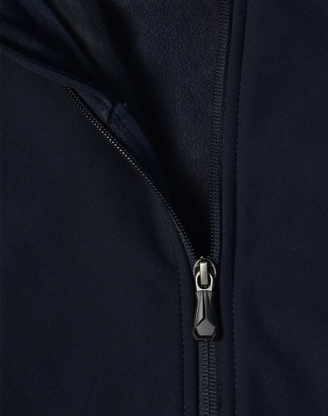 A navy softshell high-tech jacket featuring a zippered front and a fleece lining. The jacket includes a logo.