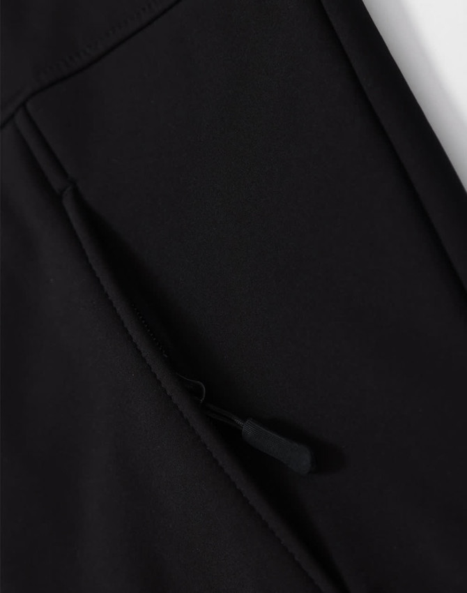 A close-up of a black softshell hoodie with a zippered side pocket and a logo.