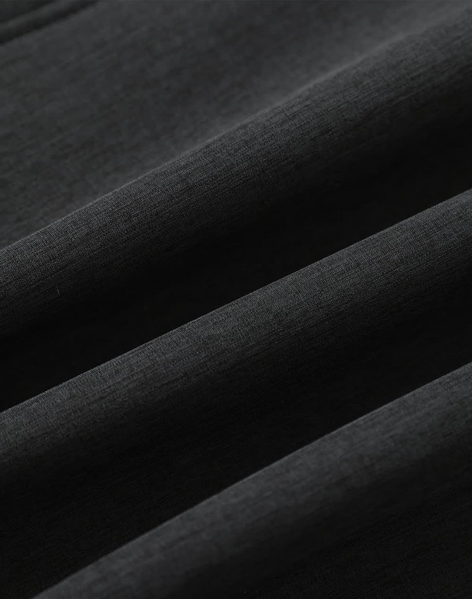 A close-up of a black softshell fabric with a smooth texture, featuring folds and creases.