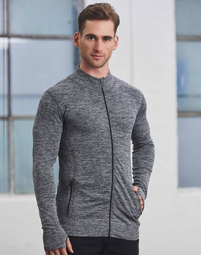 A man wearing a grey seamless jacket with a zip, featuring a fitted design and pockets.