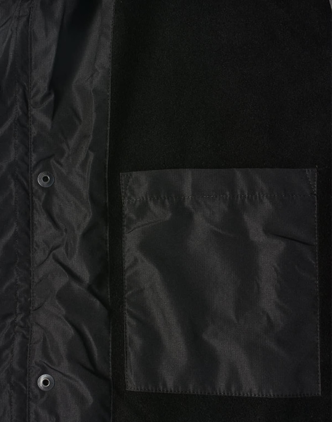 A unisex black jacket featuring a straightforward design and a chest pocket, with a small logo displayed.
