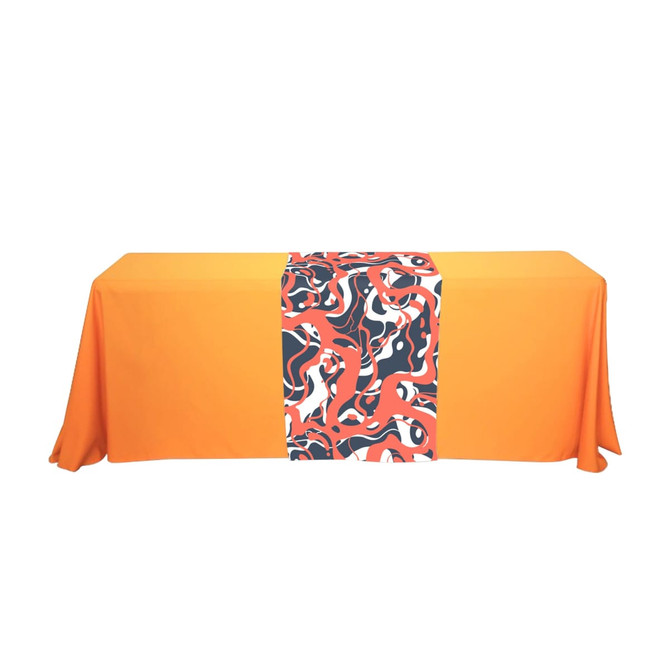 An orange table with a medium table runner featuring a vibrant abstract pattern in red, black, and white.