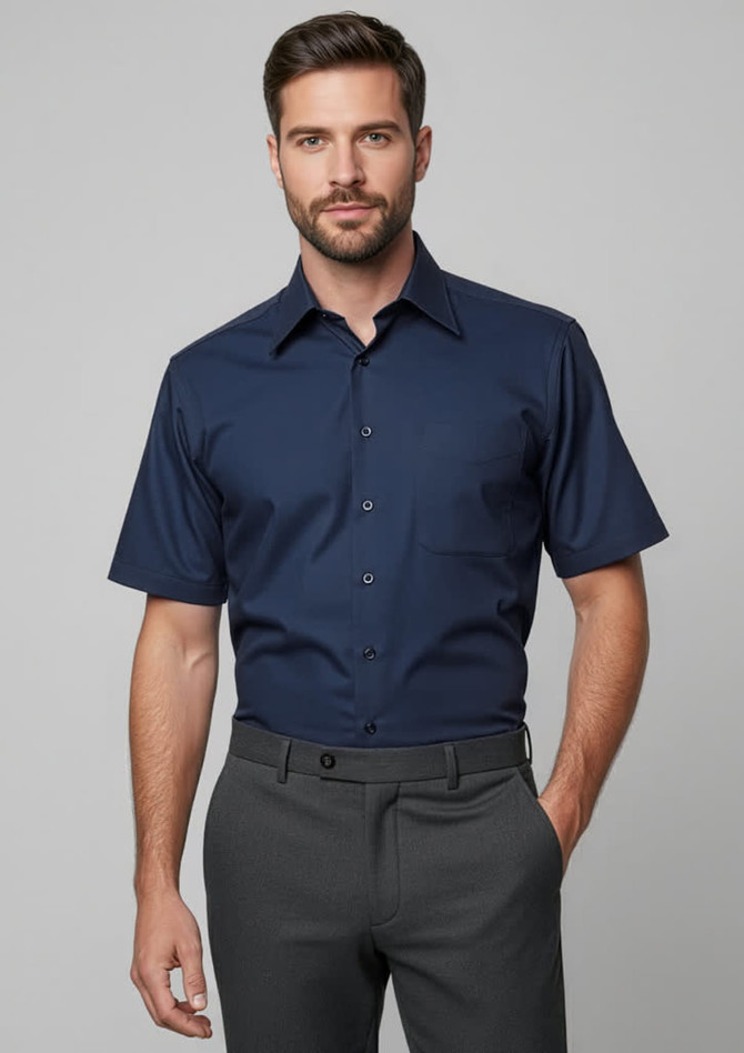 A navy short sleeve button-up shirt featuring a classic collar, worn with grey trousers. The shirt has a logo.