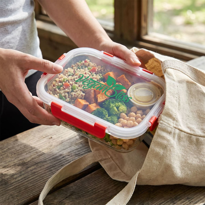 A clear lunch box filled with quinoa, roasted sweet potato, broccoli, and chickpeas, held above a tote bag.