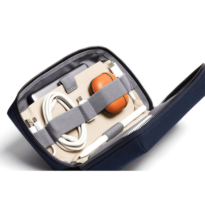 A navy tech kit containing a stylus, cables, and a case for earbuds, secured with elastic straps inside.