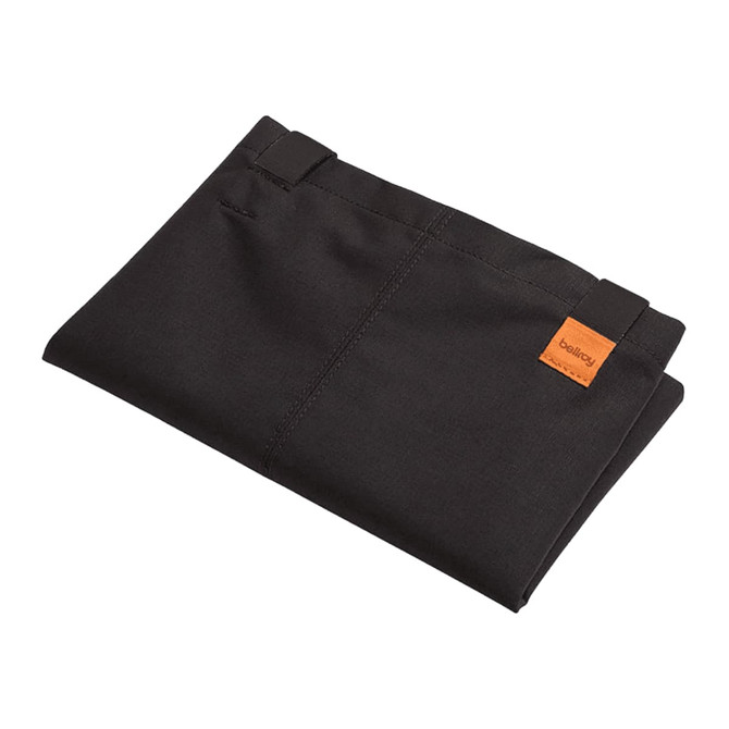 A folded black tote bag with a small logo tag, showcasing its minimalistic design and fabric texture.