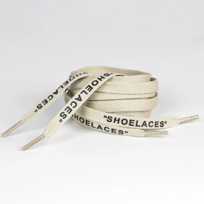A pair of cream-coloured printed shoelaces with metal tips, featuring the word "SHOELACES."