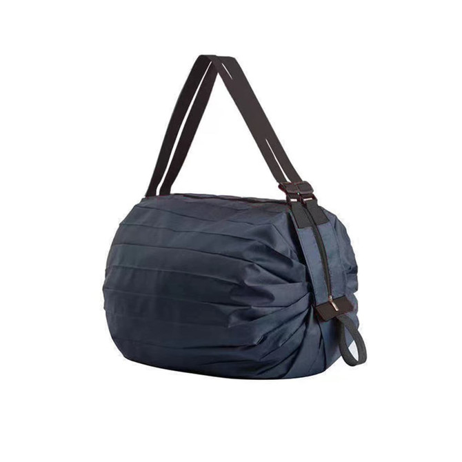 A foldable shopping shoulder bag in navy blue with black straps and a pleated design. It features a logo.