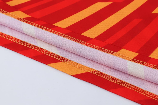 A vibrant red and orange polyester micro mesh fabric with a striped pattern, showcasing the shirt’s long sleeves and stitching.
