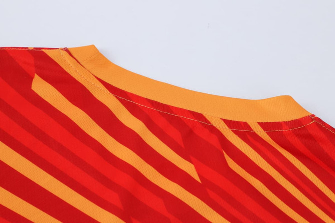 A long-sleeved shirt with a bold red and yellow striped design, featuring a crew neckline and a logo.