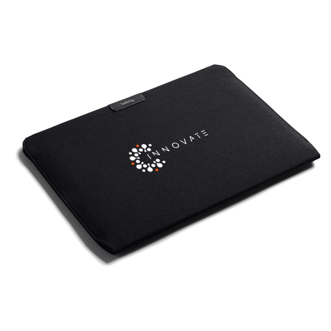 A black laptop sleeve featuring a logo on the front, designed for a 16-inch laptop.