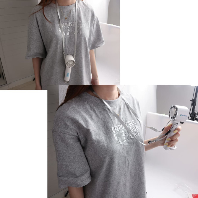 A personal cooling fan in white and blue, hanging from a grey T-shirt, held by a person.