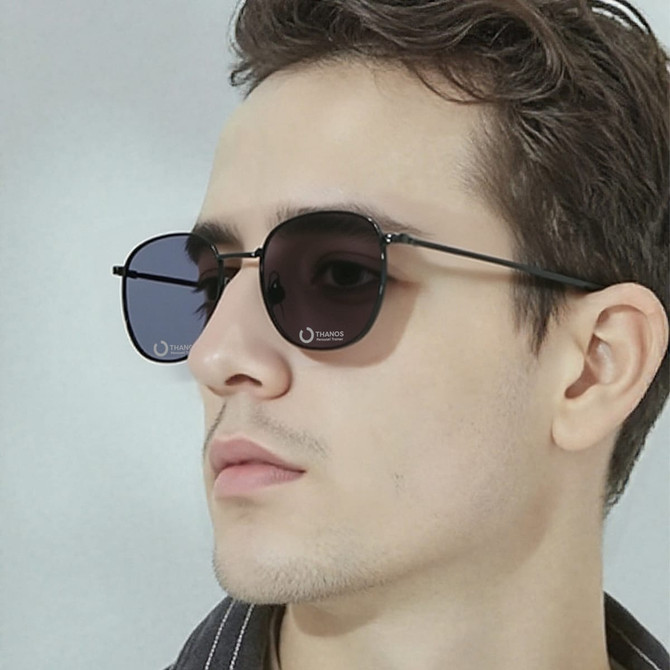 Classic metal sunglasses with dark lenses, worn by a model with light brown hair and a neutral expression.