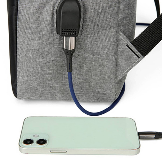A grey laptop backpack features a USB charging port connected to a phone. The backpack has black accents.