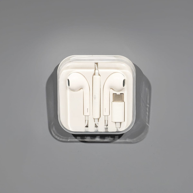 A set of white USB Type C earphones in a clear case, featuring a charging connector.