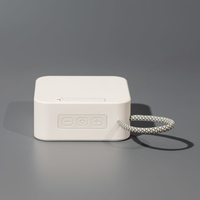 A compact white portable Bluetooth speaker with a textured carrying loop and control buttons on the side.