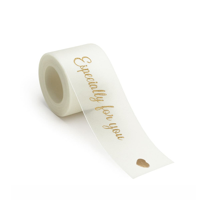 A roll of ivory organza ribbon with gold text and a small heart design. The product has a logo on the packaging.