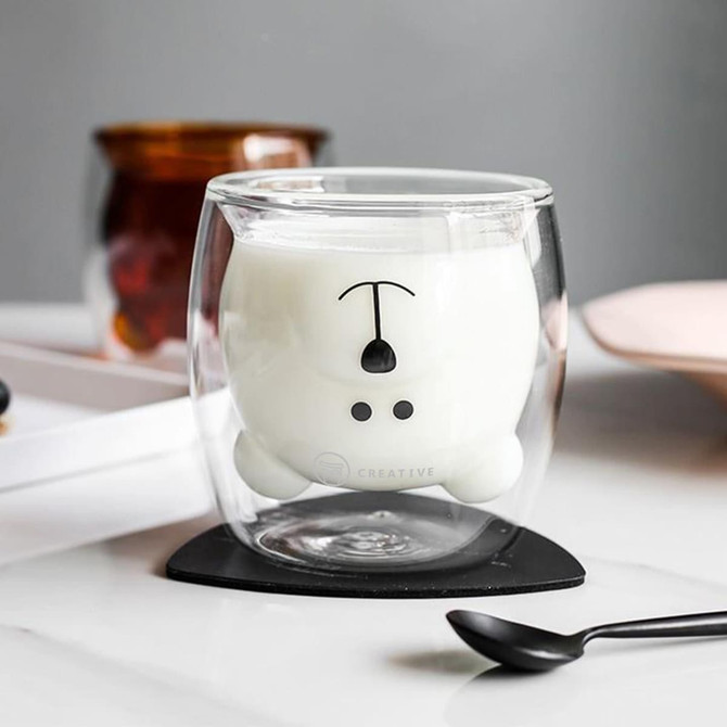 A Bear Double Wall Glass in clear and white, featuring a bear design on the bottom, with a small black spoon beside it.