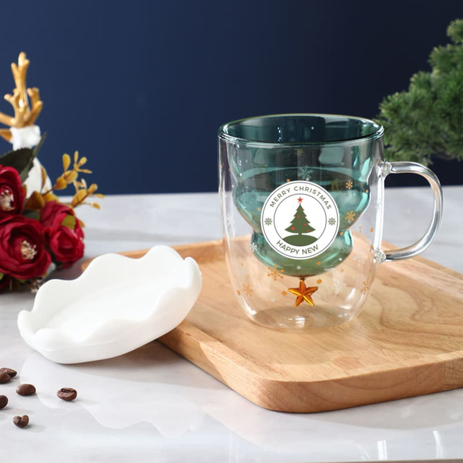 A double wall mug with a transparent design, featuring a green interior and a Christmas tree illustration, alongside a white lid.