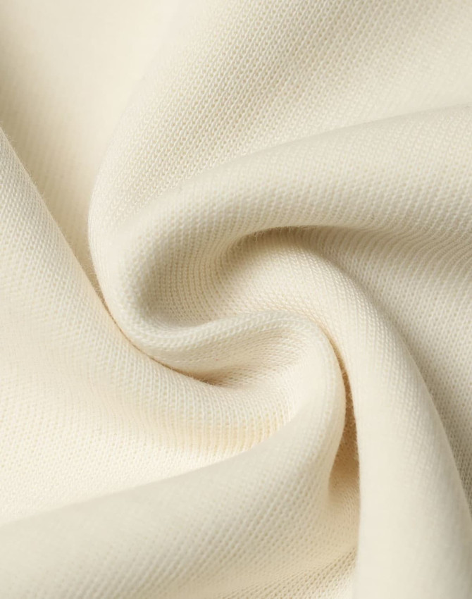 A close-up of soft, cream-coloured fabric showcasing a smooth texture and knit pattern.