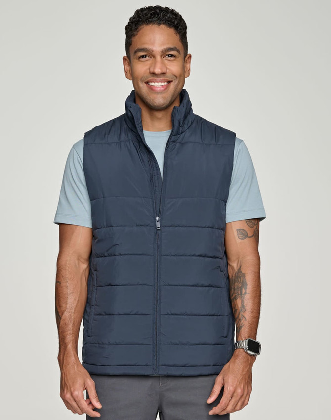 A man wearing a navy blue insulated puffer vest over a light blue shirt, smiling at the camera.