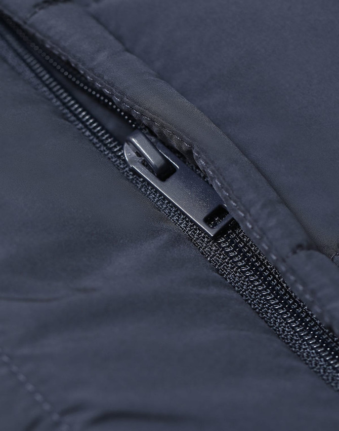 A close-up of a zip on a dark blue insulated puffer vest featuring a branded logo.