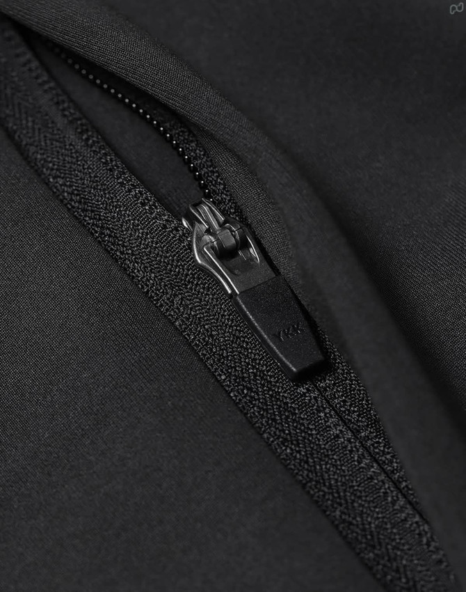 A close-up of a black softshell jacket featuring a zipper detail and a textured fabric finish.