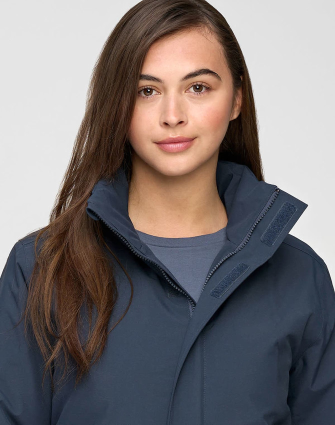 A unisex quilted waterproof jacket in navy blue, featuring a high collar and zippered front, worn by a model.
