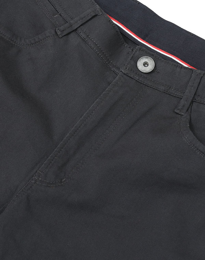 A close-up of black ladies' flexi chino pants, featuring a button and zip fly, with a hint of red and white detailing.