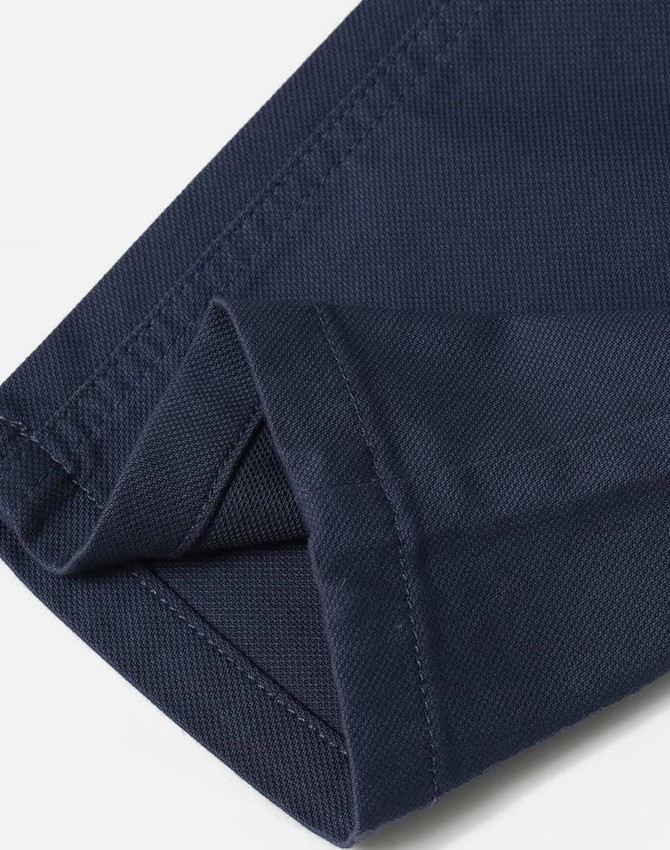 A close-up of folded navy blue chino pants featuring a smooth fabric texture and detailed stitching.