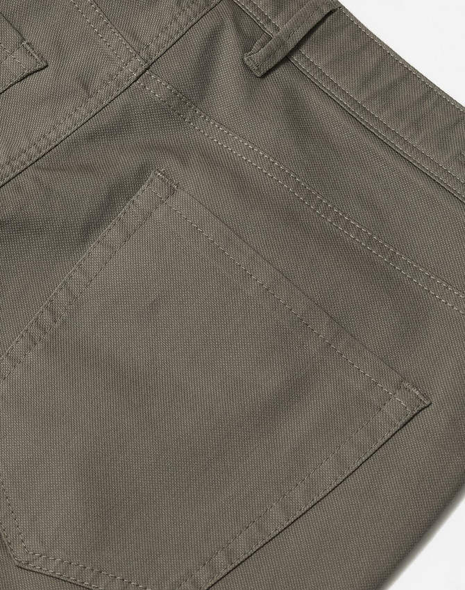 A close-up of khaki ladies' chino pants, featuring a back pocket and detailed stitching. The fabric appears flexible.