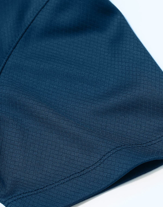 A close-up of a navy blue sustainable jacquard knit polo showing its textured fabric and stitching details.