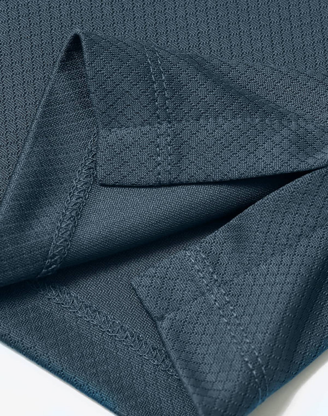 A close-up of a dark teal fabric with a jacquard knit texture and visible stitching details.