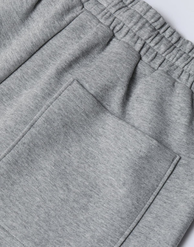 A close-up of grey unisex sweatpants featuring an elastic waistband and a back pocket.
