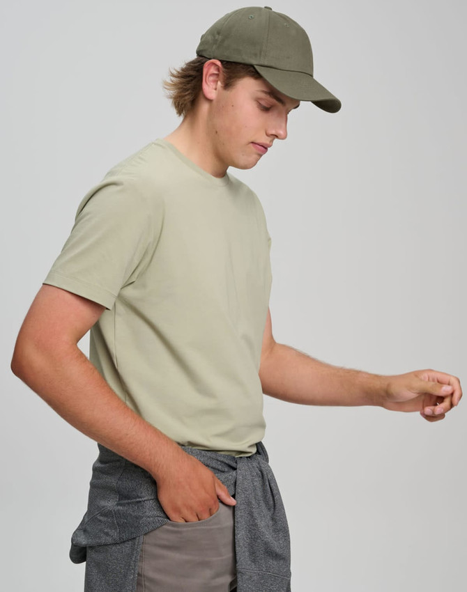 A light olive green men's premium cotton t-shirt worn with a matching cap and casual pants, featuring a logo.