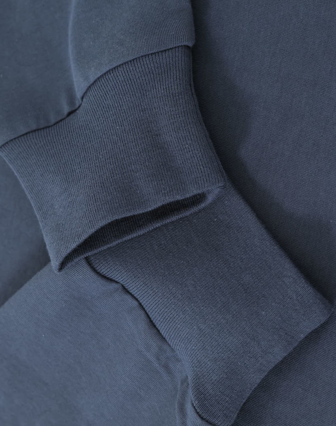 A close-up of navy blue cotton long sleeve tee shirt cuffs, featuring a subtle logo.
