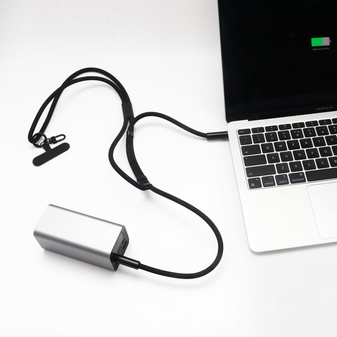 A silver charging power bank connected to a laptop with a black lanyard and cable.
