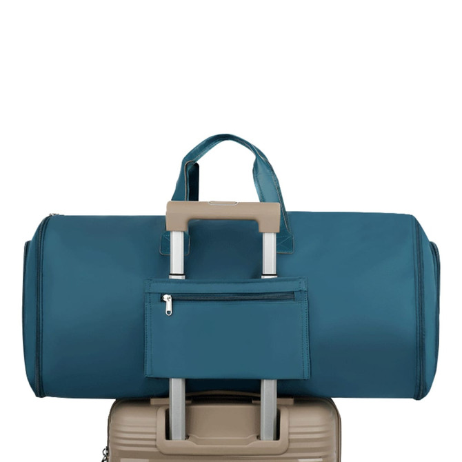 A teal duffel bag sits atop a beige suitcase, featuring a small zippered pocket on the front.