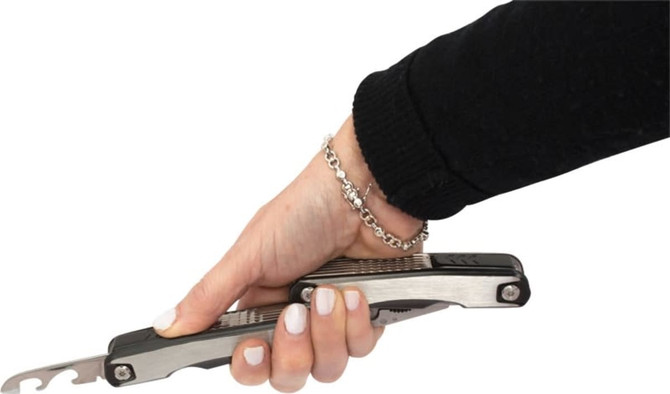 A stainless steel multi-tool held in a hand, featuring various tools and a silver chain bracelet.