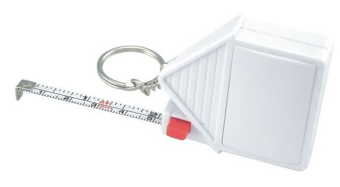 A white house-shaped tape measure with a keyring, featuring a retractable measuring tape marked in centimetres.