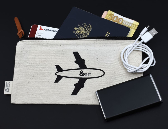 A calico travel pouch featuring an airplane design, containing a passport, cash, and charging cables.