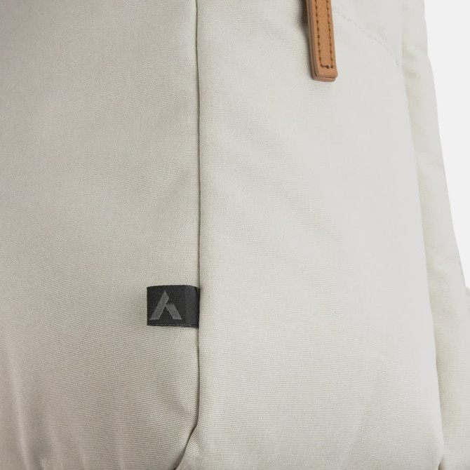 A beige backpack with a textured surface and leather accents, featuring a small logo on the side.