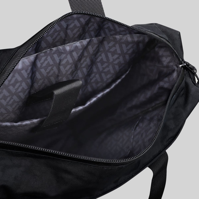 A black tote bag with an interior featuring a patterned lining and compartments for organisation. It has a logo.