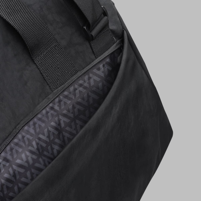A black duffle bag featuring a patterned inner lining and adjustable straps. It has one visible pocket.