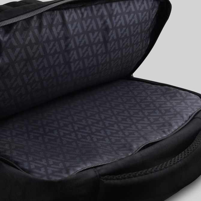 An open black backpack revealing a patterned inner lining and spacious compartment. The bag has a sleek design.