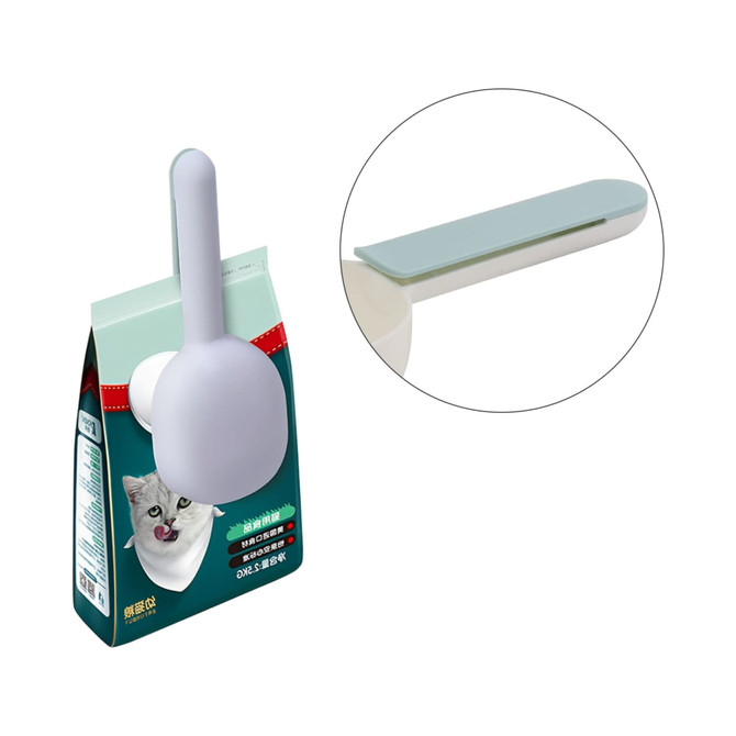 A pet food scoop in light grey attached to a green packaging. The scoop features a flat edge for easy use.