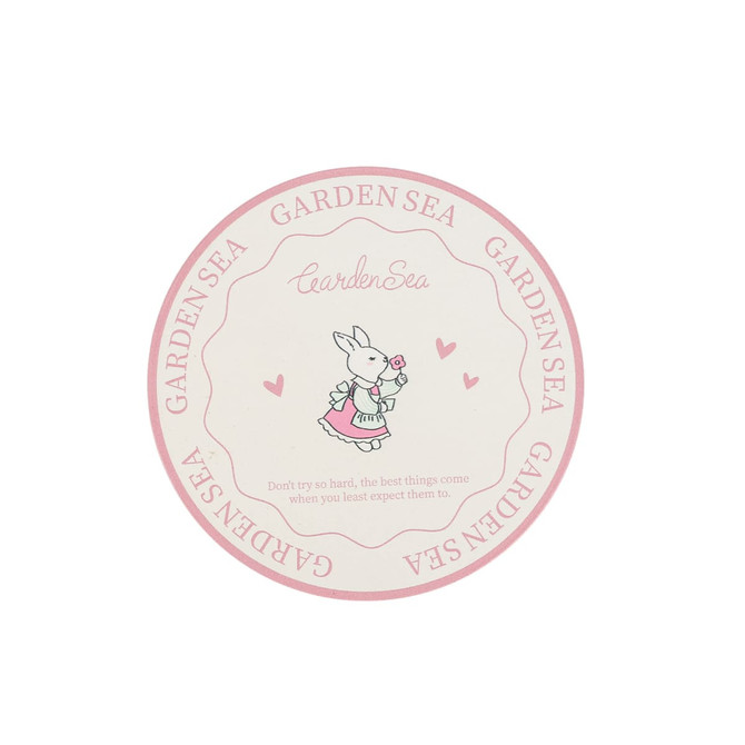 A round PU coaster featuring a pink and cream design with a cute bunny illustration and a logo.