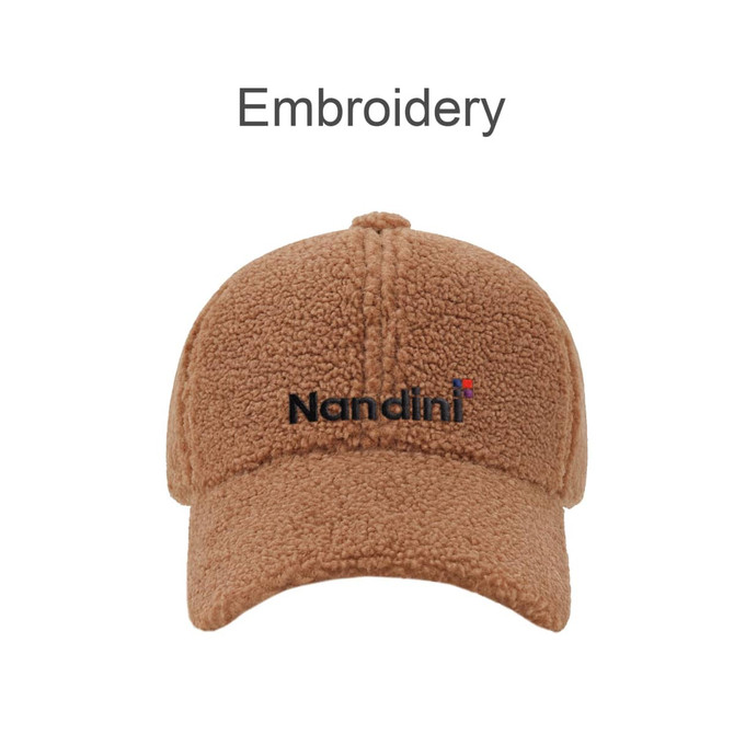 A tan lamb fur baseball cap with a curved brim and a logo embroidered on the front.