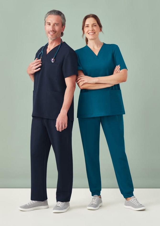 A navy blue scrub top and teal scrub top worn by a man and a woman, both paired with matching pants and casual shoes.