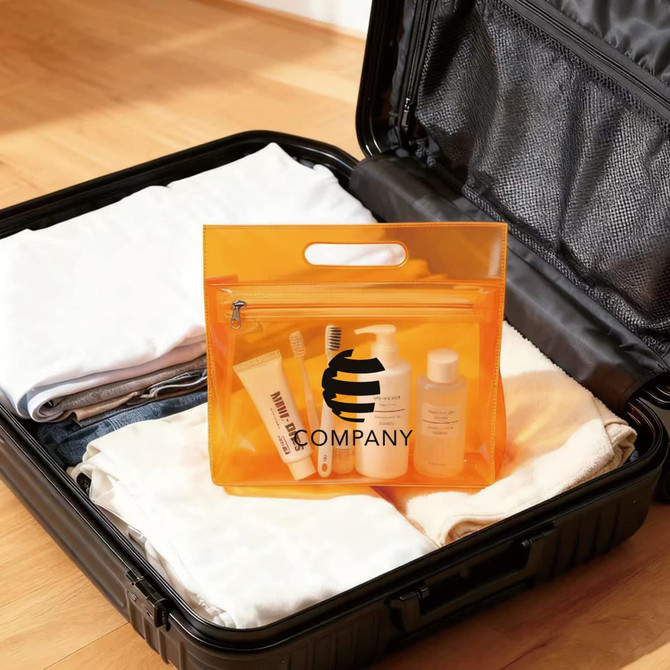 An orange transparent cosmetic pouch filled with toiletries, placed inside a suitcase alongside folded clothes.